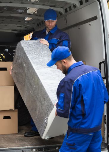 Movers loading wrapped furniture into a removal van